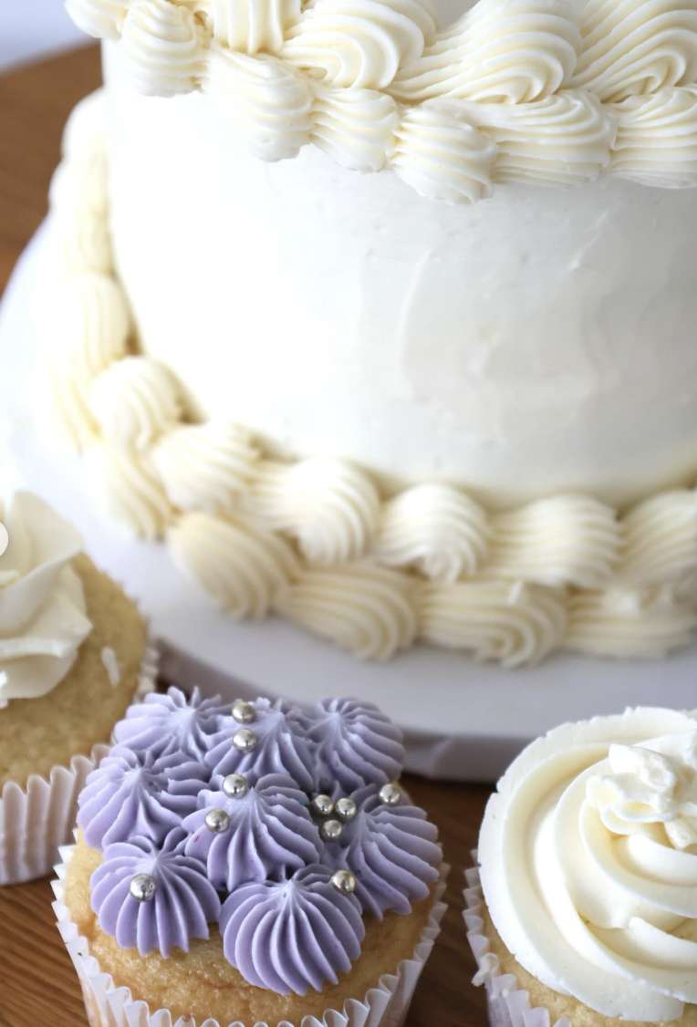 White buttercream tiered cake with lavender cupcake — texture detail