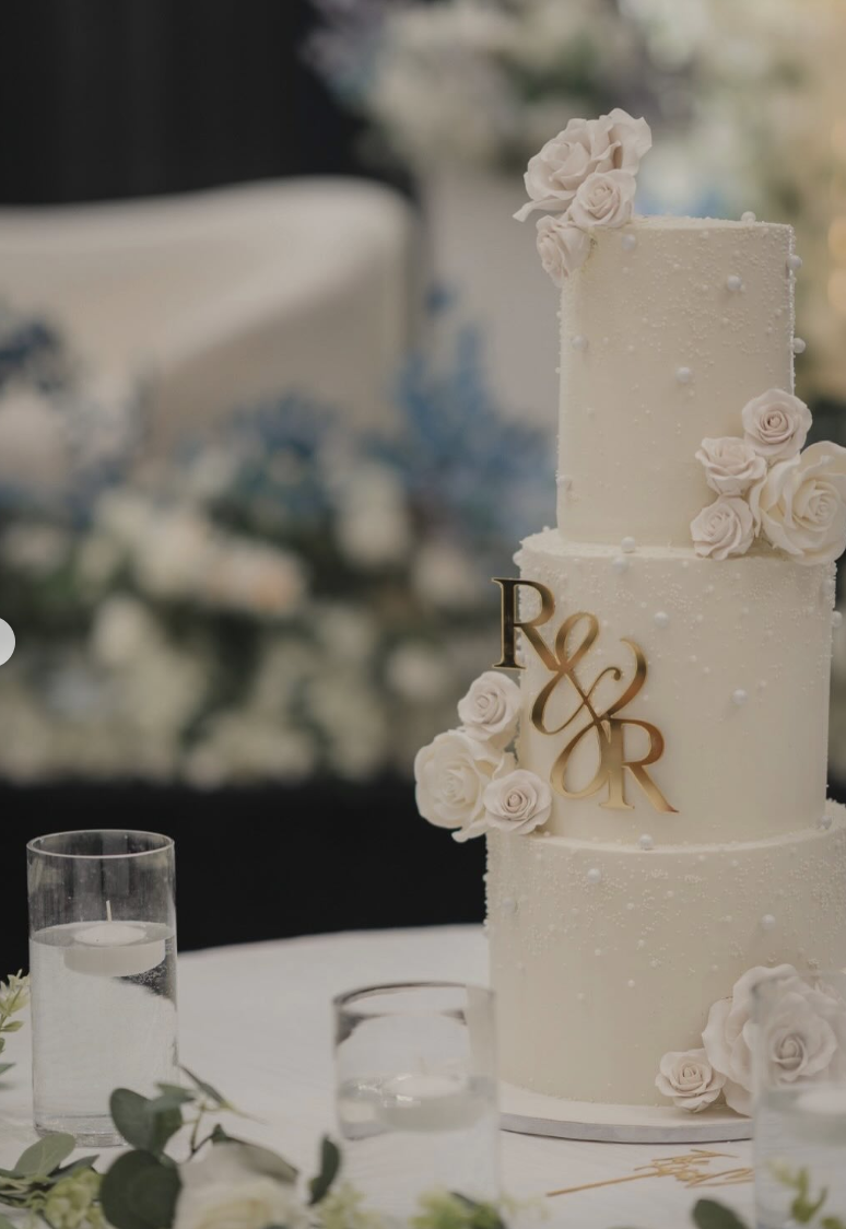Three-tier white wedding cake with sugar roses and gold R&R monogram — The Treat Fairy